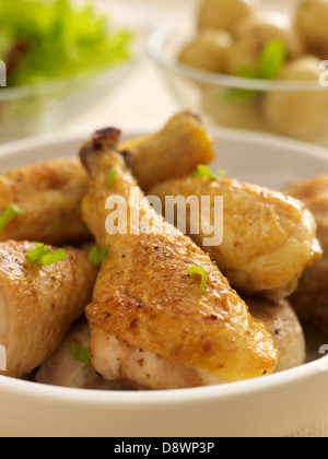 Pollo cosce di pollo disossate di pezzi di vetro bianco ciotole insalata di patate condimento Foto Stock