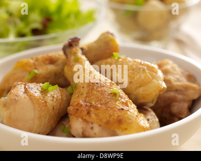 Pollo cosce di pollo disossate di pezzi di vetro bianco ciotole insalata di patate condimento Foto Stock