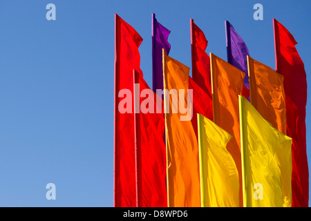 Molte bandiere a colori sul vento con cielo blu chiaro dietro Foto Stock