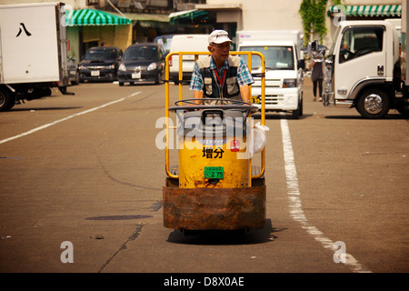 Giapponese di mezza età uomo alla guida di un carrello a motore presso il parcheggio del mercato del pesce Tsukiji a Tokyo Foto Stock