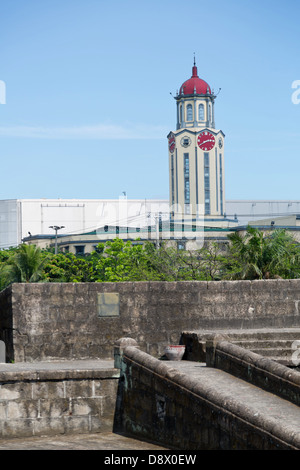 Vista su una torre orologio oltre le mura della città di Intramouros a Manila nelle Filippine Foto Stock