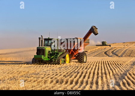 John Deer trattore tirando il Brent Bank fuori del carro, mietitura del grano. Foto Stock