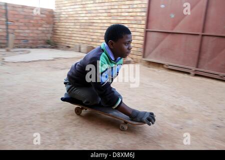 JOHANNESBURG, SUD AFRICA: Thabang Diholo il 5 giugno, 2013, a Johannesburg, in Sud Africa. Data di nascita paraplegico, Diholo è legato in sedia a rotelle ma preferisce spostarsi usando un vecchio skateboard. Il 16-anno-vecchio non richiede alcun trattamento speciale dai suoi coetanei ed è determinata a studiare ulteriormente, verso una vita migliore. (Foto di Gallo Immagini / Sowetan / Bafana Mahlangu) Foto Stock