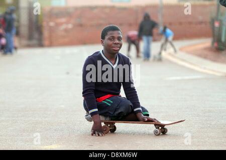 JOHANNESBURG, SUD AFRICA: Thabang Diholo il 5 giugno, 2013, a Johannesburg, in Sud Africa. Data di nascita paraplegico, Diholo è legato in sedia a rotelle ma preferisce spostarsi usando un vecchio skateboard. Il 16-anno-vecchio non richiede alcun trattamento speciale dai suoi coetanei ed è determinata a studiare ulteriormente, verso una vita migliore. (Foto di Gallo Immagini / Sowetan / Bafana Mahlangu) Foto Stock