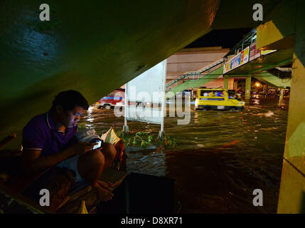 Davao, Filippine. Il 6 giugno 2013. Un filippino residente soggiorno sotto ponte mentre automobilista passa su acqua di inondazione causata da una forte pioggia a Davao City, nel sud delle Filippine, 06 giugno 2013.Il filippino atmosferica, geofisici e astronomici di amministrazione dei servizi (PAG-ASA) ha detto che una zona di convergenza intertropicale ITCZ () pregiudicare il sud della maggior parte delle Filippine che innesca hi livello di acqua di inondazione in città. Credito: Eli Ritchie Tongo/Alamy Live News Foto Stock