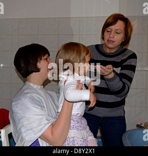 2 anno di età bambina avente il suo primo taglio di capelli Foto Stock