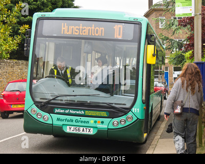 Donna di salire a bordo di un bus rurale in Heacham, Norfolk e pagando il conducente la sua tariffa. Foto Stock