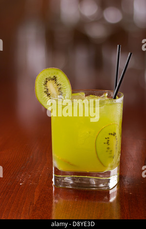 Verde kiwi cocktail serviti su un segnale di occupato al di fuori della messa a fuoco bar guarnito con una fresca fetta di kiwi Foto Stock