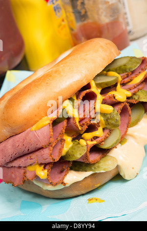 Una pianura bagel riempito con pastrami, fette di cetriolini, la senape e il peperoncino maionese. Foto Stock