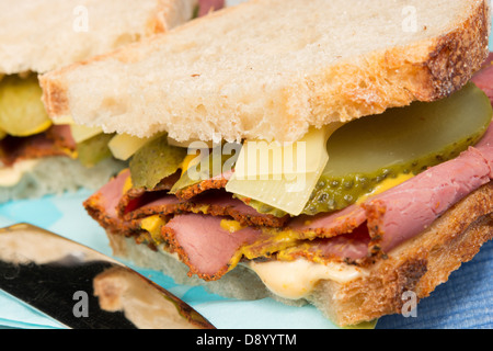 Un deli in stile di sandwich pastrami, formaggio Groviera, fette di cetriolini, la senape e il peperoncino maionese sul pane a lievitazione naturale. Foto Stock