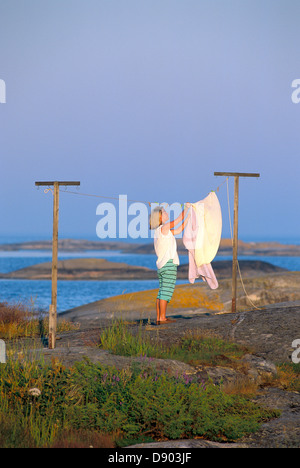 La donna è i panni appesi ad asciugare, Gilloga, arcipelago di Stoccolma, Svezia. Foto Stock