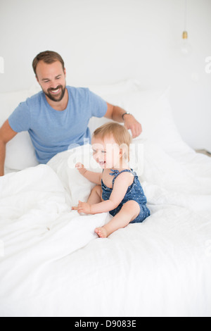 Padre e figlia piccola giocando a letto Foto Stock