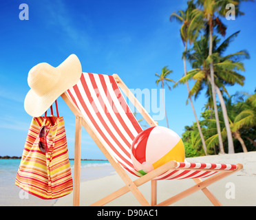 Sedia spiaggia con accessori su una spiaggia tropicale con palme Foto Stock