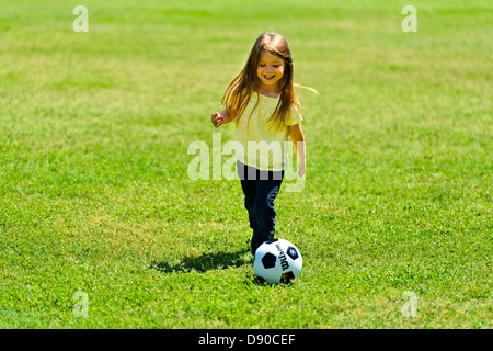 Giovane ragazza calcia palla di calcio. Foto Stock