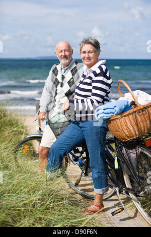 Coppia senior con le biciclette al mare Foto Stock