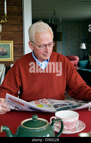 Alti uomini quotidiano di lettura al tavolo da pranzo Foto Stock