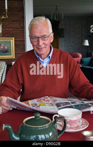 Alti uomini quotidiano di lettura al tavolo da pranzo Foto Stock