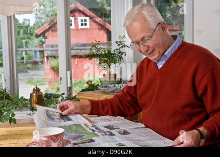 Alti uomini quotidiano di lettura al tavolo da pranzo Foto Stock