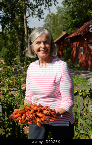 Senior donna tenendo la piastra di cray pesce in giardino Foto Stock