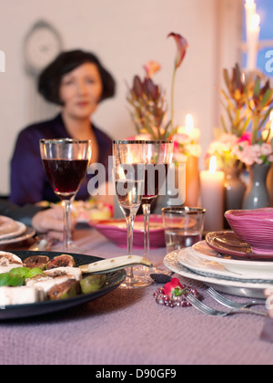 Donna seduta in elegante tavolo da pranzo Foto Stock