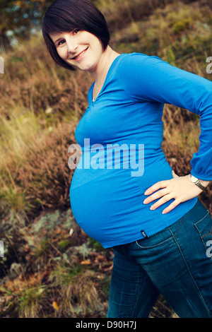 Donna incinta in piedi sull'erba Foto Stock
