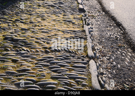 Pietre poste in lineari e modelli a spina di pesce per formare marciapiede e grondaia al di fuori di una terrazza di case, Llanrhystud, Wales, Regno Unito. Foto Stock