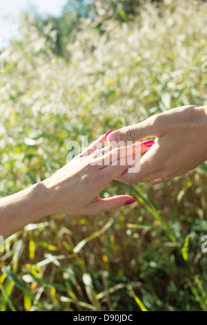 Vista ravvicinata di man mano che tiene womans mano in piena luce solare Foto Stock
