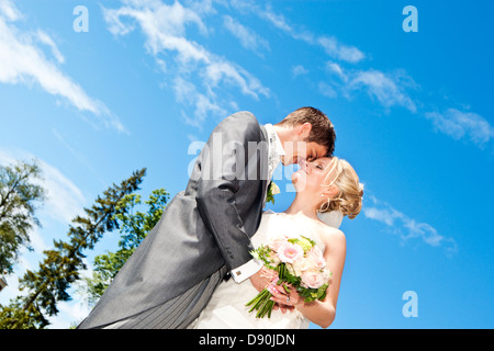 A basso angolo di vista lo sposo e la sposa che abbraccia all'aperto Foto Stock