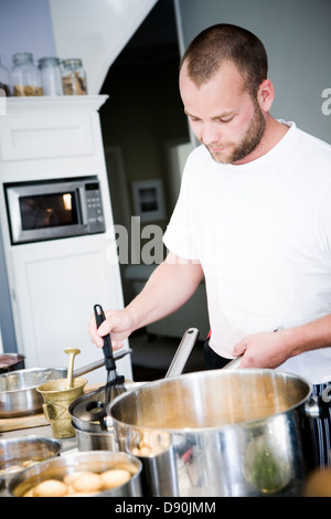 Tre quarti di vista frontale dell'uomo per la cottura in cucina domestica Foto Stock