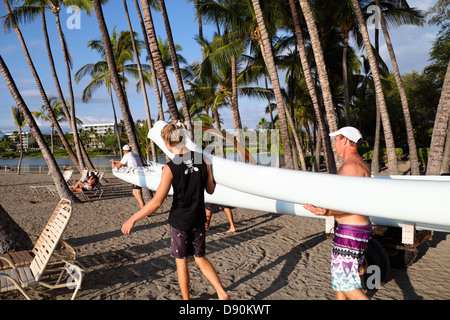 I soci del Club portano la canoa outrigger al litorale di Anaehoomalu Bay in Waikoloa sulla Big Island delle Hawaii Foto Stock