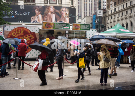 Gli amanti della ciambella brave versando pioggia in Herald Square a New York per una libera Krispy Kreme ciambella Foto Stock