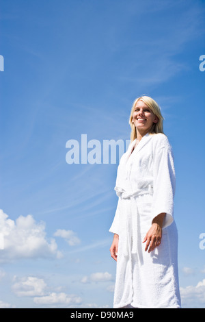 Donna in accappatoio in piedi, sorridente Foto Stock