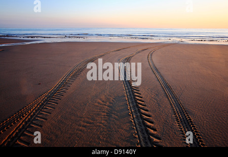 Una vista di tracce su una spiaggia che conduce al mare di mattina presto. Foto Stock