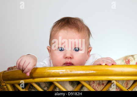 Baby boy è guardare attraverso una parte superiore della sedia vintage Foto Stock