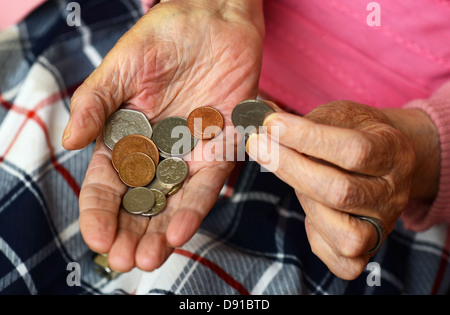 Soldi, monete in una donna anziana con le mani in mano, close up di denaro contante nelle mani della donna anziana Foto Stock