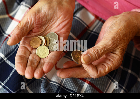 Soldi, monete in una donna anziana con le mani in mano, close up di denaro contante nelle mani della donna anziana Foto Stock