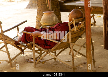 Un monaco si appoggia durante il calore del giorno a Shwe In Bin Kyaung monastero di Mandalay Foto Stock