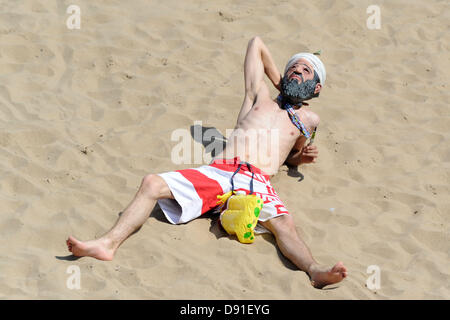 Porthcawl, South Wales, Regno Unito 8 Giugno 2013. Il clima caldo attrae folle di Porthcawl beach in Galles del sud su uno dei giorni più caldi dell'anno. Un giovane uomo sunbathes con un Osama Bin Laden sulla maschera a Porthcawl beach. Credito: Matteo Horwood/Alamy Live News Foto Stock