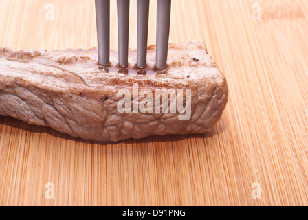 Carni bovine con forcella su un sfondo di legno Foto Stock