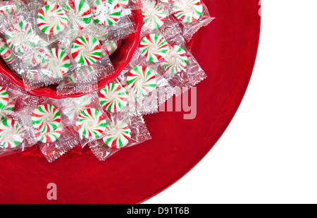 La girandola Natale caramelle visualizzato in rosso ciotola e la piastra su bianco Foto Stock