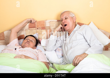 Assonnato senior l uomo e la donna a sbadigliare a letto Foto Stock