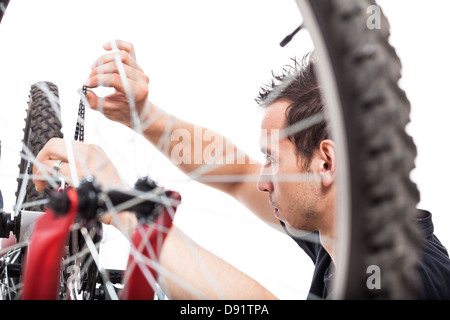 Giovane uomo Regolazione catena di bicicletta e la riparazione di biciclette, isolati su sfondo bianco Foto Stock