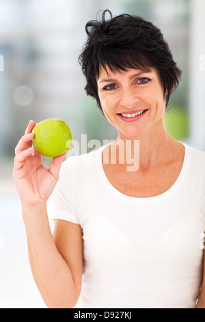 Bella donna di mezza età tenendo una mela verde Foto Stock