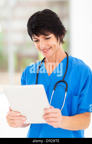 Felice di mezza età lavoratore medico utilizzando tablet pc in ufficio Foto Stock