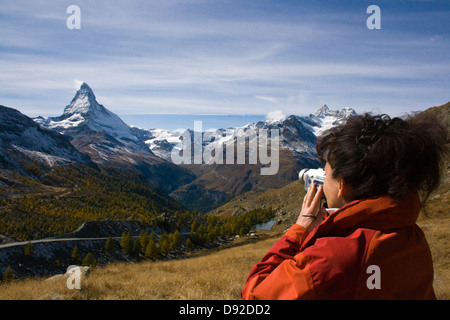 Donna in giacca rossa scattando una foto di Matterhorn-Frau A roter Jacke richtet ihre Video-Kamera auf das Matterhorn Foto Stock