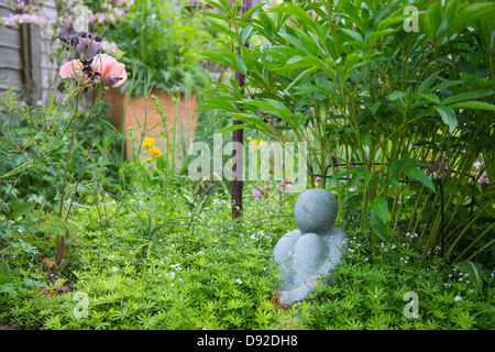 La vista del giardino con una piccola statua tra i confini. Foto Stock