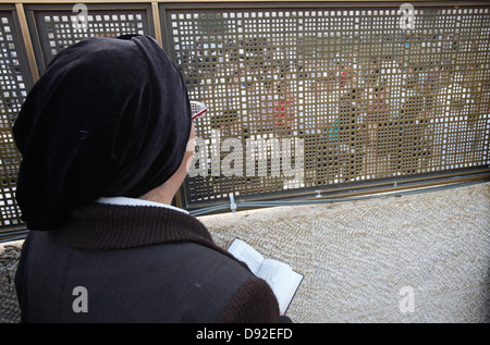 Una religiosa ebrea guardando attraverso il metallo perforato recinto dividendo maschio e femmina la preghiera di area di sezione presso il Muro occidentale o Muro del pianto la Città Vecchia di Gerusalemme Est Israele Foto Stock