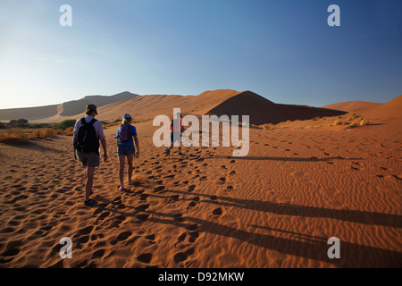Famiglia di arrampicata duna di sabbia accanto a Deadvlei, vicino al Sossusvlei, Namib-Naukluft National Park, Namibia, Africa Foto Stock
