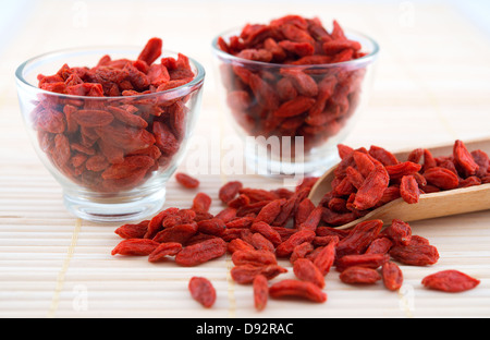 Rosso essiccato goji bacche, wolfberry o lycium, cinese la medicina di erbe vicino sul tappetino di bambù. Lycium barbarum. Foto Stock