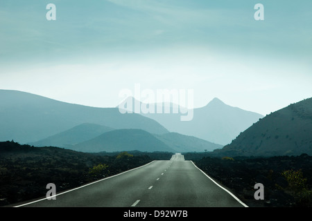 Svuotare strada che conduce verso le montagne in Lanzarote, Isole Canarie, Spagna Foto Stock